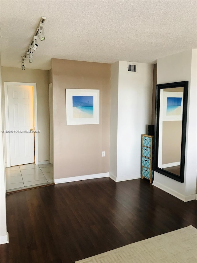 unfurnished room featuring a textured ceiling and dark hardwood / wood-style floors