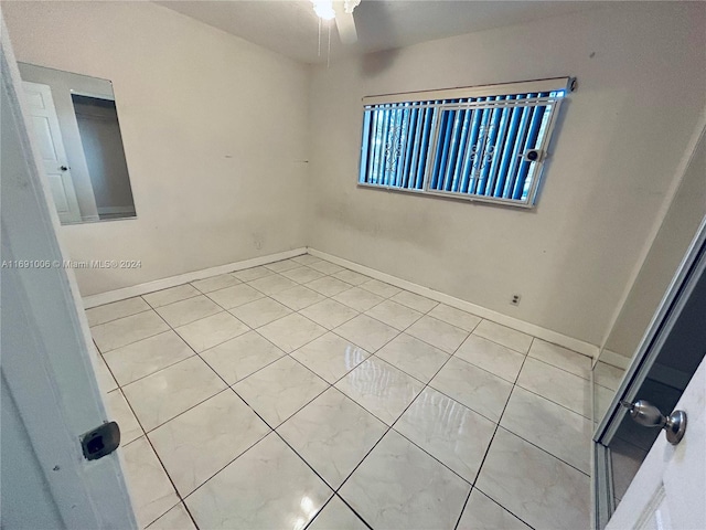 empty room with ceiling fan and light tile patterned flooring