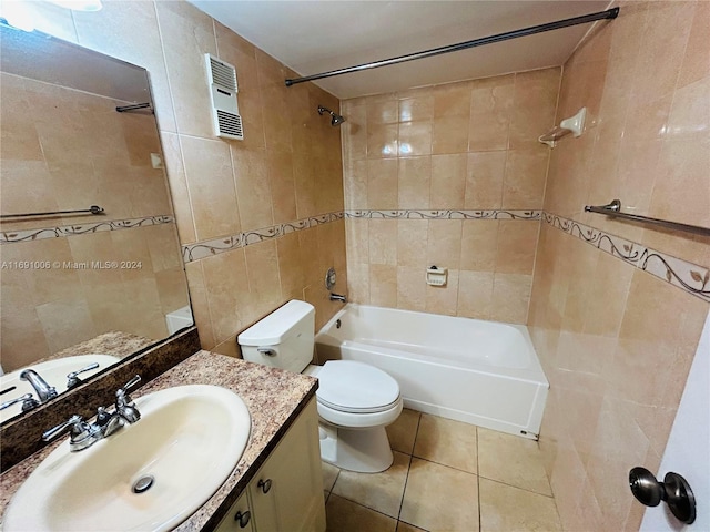 full bathroom with vanity, tile patterned floors, tiled shower / bath, toilet, and tile walls