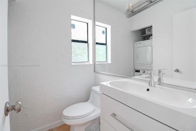 bathroom with vanity, stacked washer and clothes dryer, and toilet