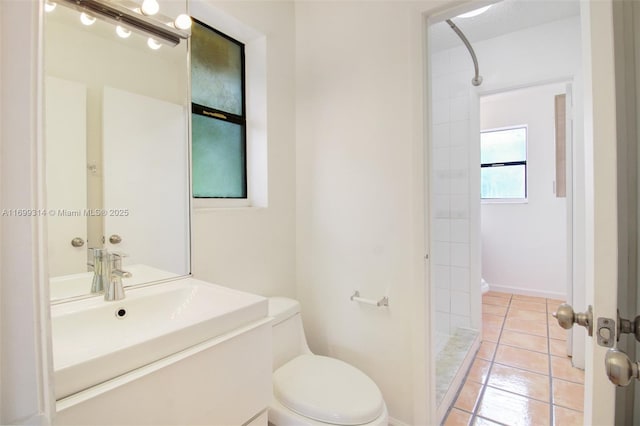 bathroom featuring a tile shower, tile patterned floors, vanity, and toilet