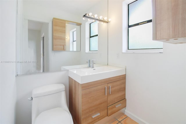 bathroom with tile patterned flooring, vanity, a healthy amount of sunlight, and toilet