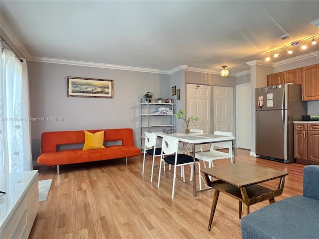 dining area featuring rail lighting, light hardwood / wood-style floors, and crown molding