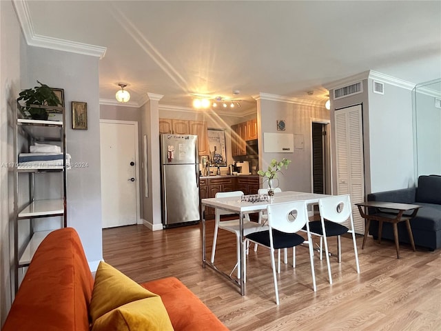 dining area featuring light hardwood / wood-style floors, sink, and crown molding