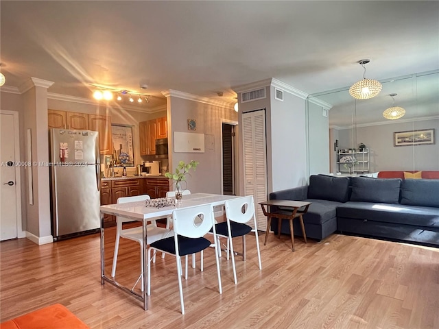 dining room with light wood-type flooring, crown molding, and sink