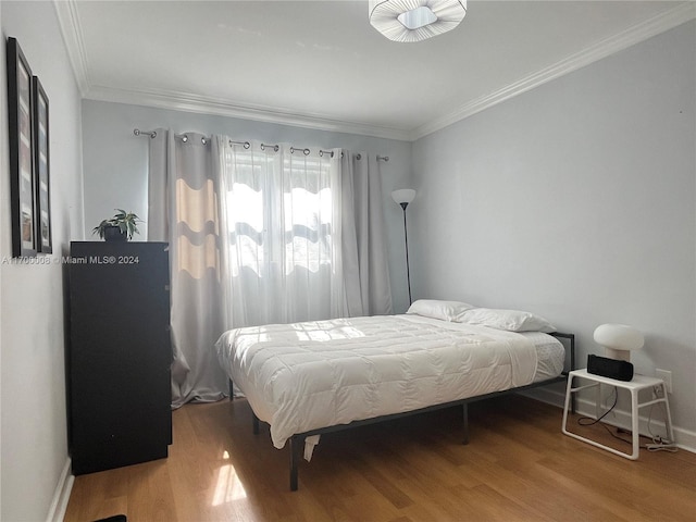 bedroom with ornamental molding and hardwood / wood-style flooring