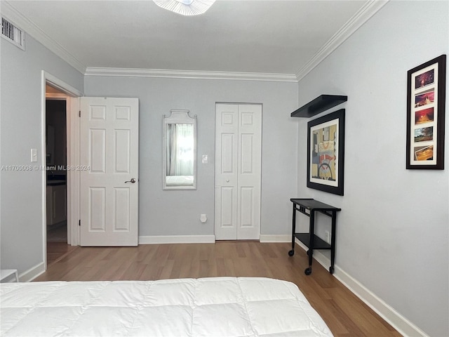 bedroom with hardwood / wood-style floors, a closet, and crown molding