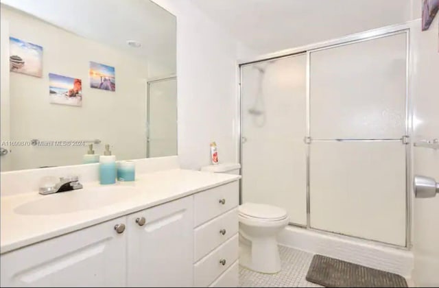 bathroom with tile patterned flooring, a shower with door, vanity, and toilet