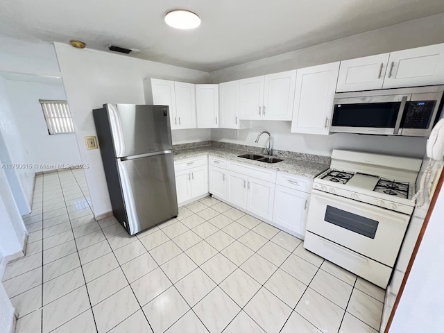 kitchen with appliances with stainless steel finishes, light stone counters, sink, white cabinets, and light tile patterned flooring