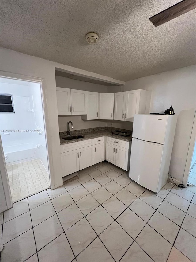 kitchen featuring white cabinetry, sink, white fridge, and a textured ceiling