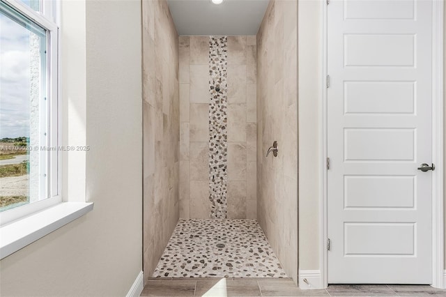 bathroom with a tile shower, tile patterned floors, and plenty of natural light