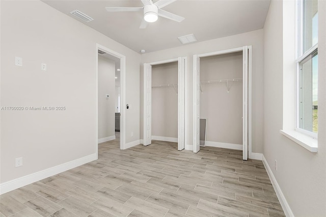 unfurnished bedroom featuring ceiling fan, two closets, and light hardwood / wood-style flooring