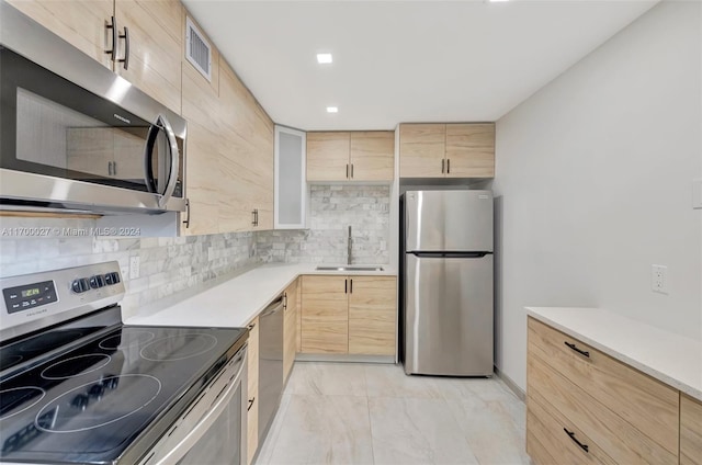 kitchen featuring light brown cabinetry, decorative backsplash, sink, and stainless steel appliances