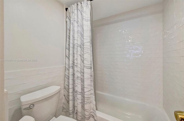 bathroom featuring shower / bathtub combination with curtain, tile walls, and toilet