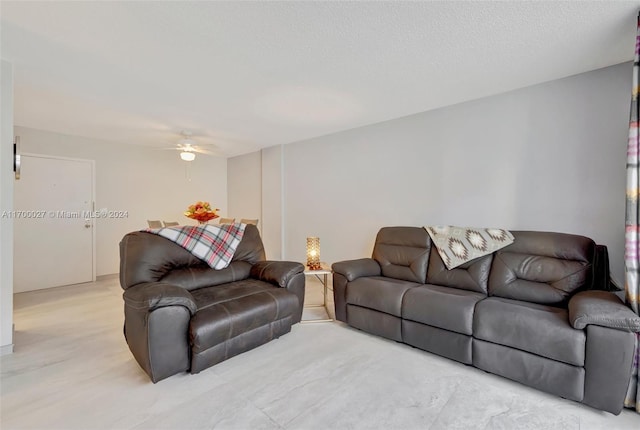 living room featuring ceiling fan and a textured ceiling