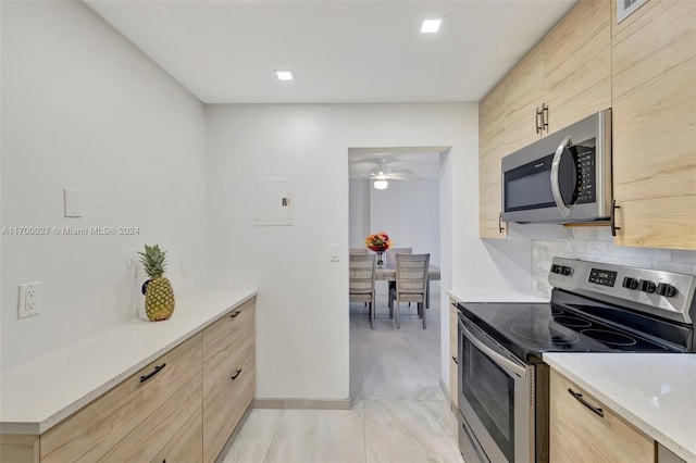 kitchen with appliances with stainless steel finishes, light stone counters, ceiling fan, and light brown cabinetry