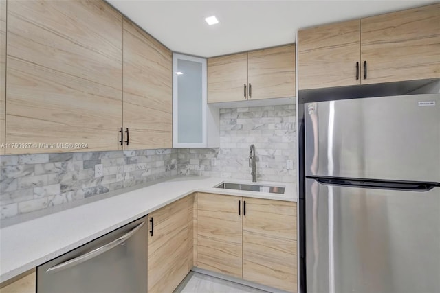 kitchen featuring decorative backsplash, appliances with stainless steel finishes, light brown cabinetry, and sink