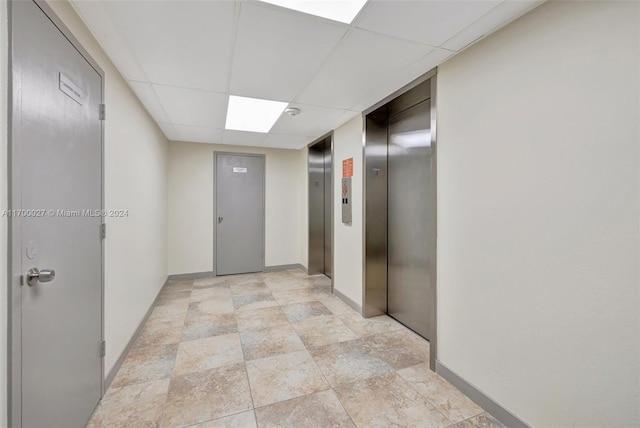 hall featuring a paneled ceiling and elevator