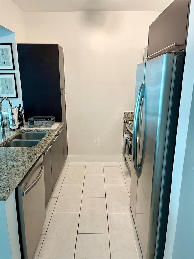 kitchen featuring dark stone counters, sink, light tile patterned flooring, and stainless steel appliances