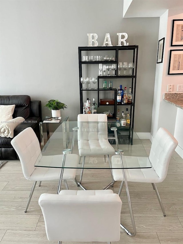 dining area with wood-type flooring and indoor bar