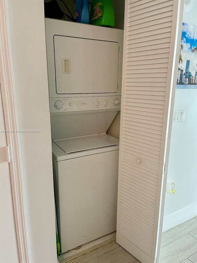 clothes washing area with light hardwood / wood-style floors and stacked washer and clothes dryer