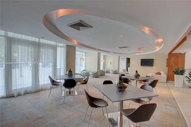 dining area with light colored carpet and a raised ceiling