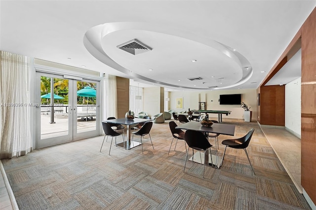 carpeted dining area featuring french doors and a raised ceiling