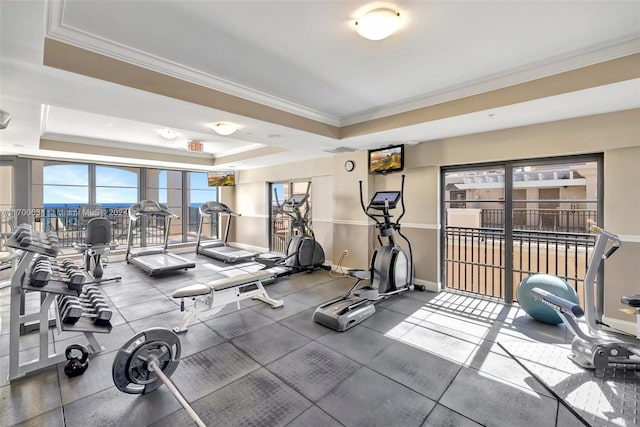 gym featuring a raised ceiling and crown molding