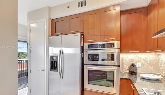 kitchen featuring light stone countertops, backsplash, and stainless steel appliances