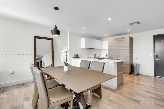 dining space featuring light wood-type flooring and sink