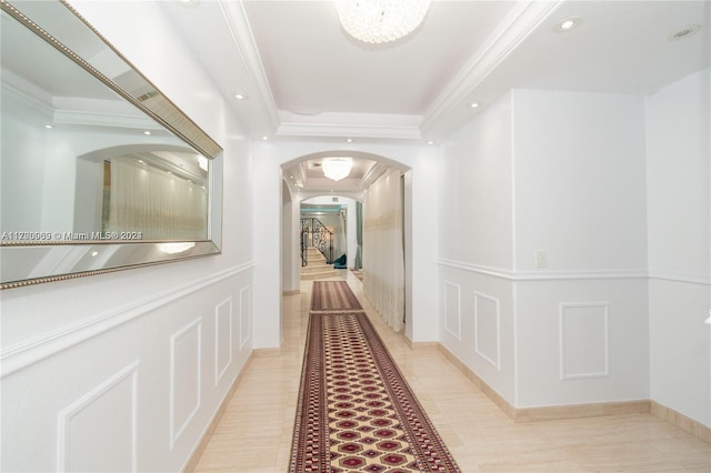 hallway featuring a raised ceiling, light tile patterned floors, and ornamental molding