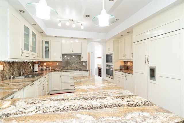 kitchen with built in appliances, light stone counters, and decorative light fixtures