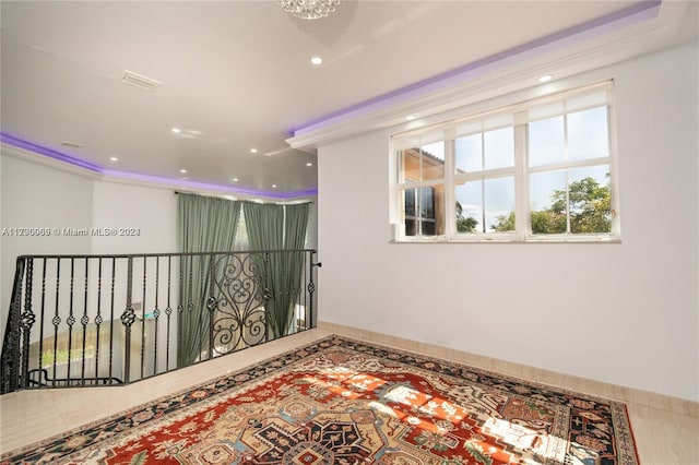 tiled spare room with a notable chandelier and ornamental molding