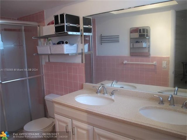 bathroom with vanity, a shower with door, toilet, and tile walls