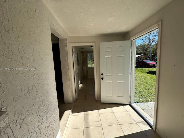 entryway with light tile patterned floors and a textured ceiling