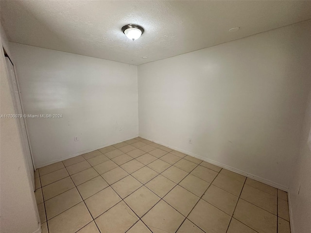 empty room with light tile patterned floors and a textured ceiling