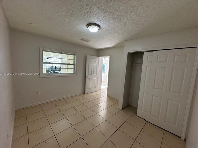 unfurnished bedroom with a closet, light tile patterned floors, and a textured ceiling