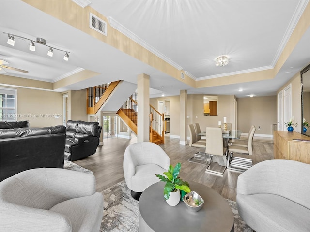 living room with a tray ceiling, ceiling fan, ornamental molding, and hardwood / wood-style flooring