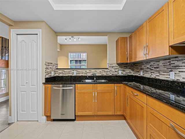 kitchen featuring backsplash, dark stone countertops, dishwasher, and sink