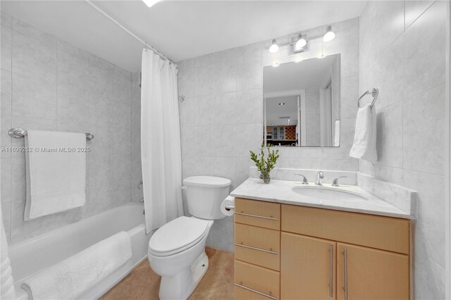 full bathroom with tile patterned flooring, shower / bath combo, vanity, and tile walls