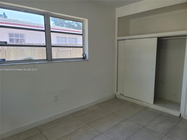 unfurnished bedroom with light tile patterned floors and a closet