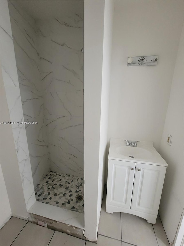 bathroom featuring tile patterned flooring, vanity, and tiled shower