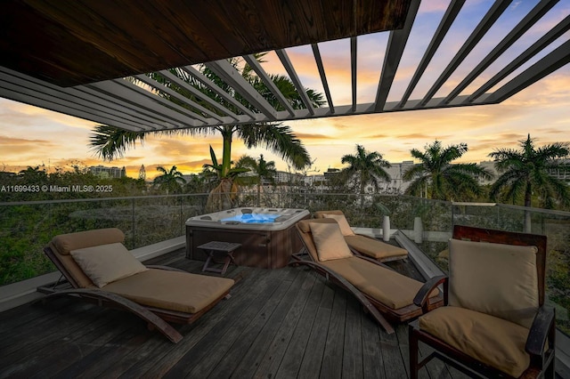 deck at dusk featuring a hot tub and a pergola