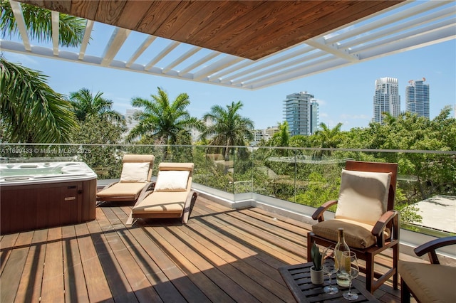 wooden terrace with a city view, a hot tub, and a pergola