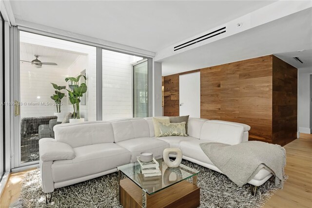 living area featuring light wood-style floors, wooden walls, and visible vents