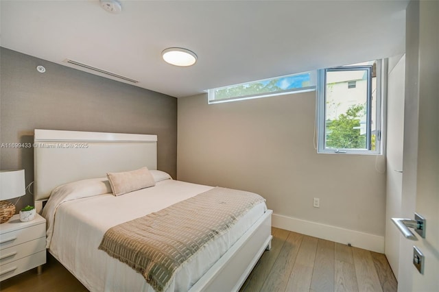 bedroom featuring visible vents, baseboards, and wood finished floors