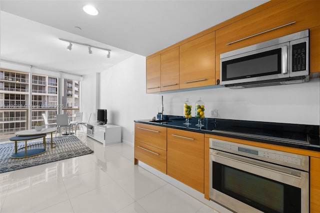 kitchen featuring appliances with stainless steel finishes, light tile patterned floors, and rail lighting