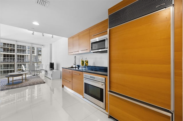 kitchen featuring appliances with stainless steel finishes, light tile patterned flooring, sink, and rail lighting