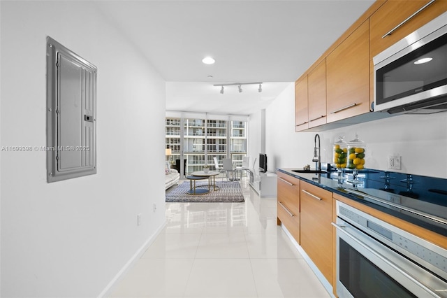 kitchen with sink, electric panel, light tile patterned flooring, track lighting, and appliances with stainless steel finishes