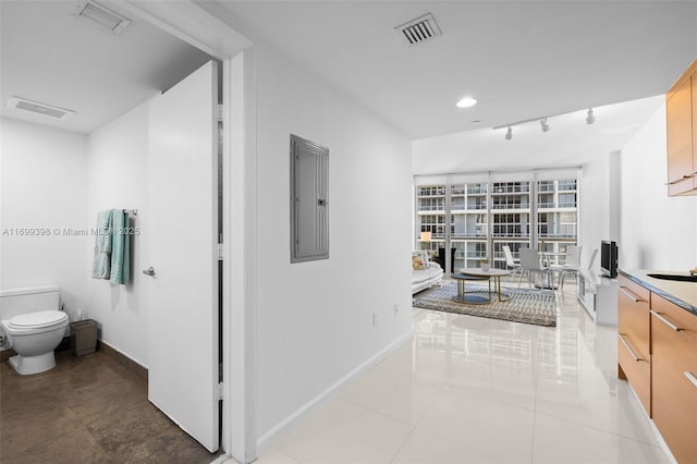 interior space with electric panel, toilet, tile patterned floors, and rail lighting